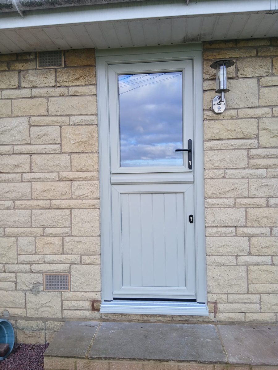 Light grey uPVC stable-style back door in a stone wall