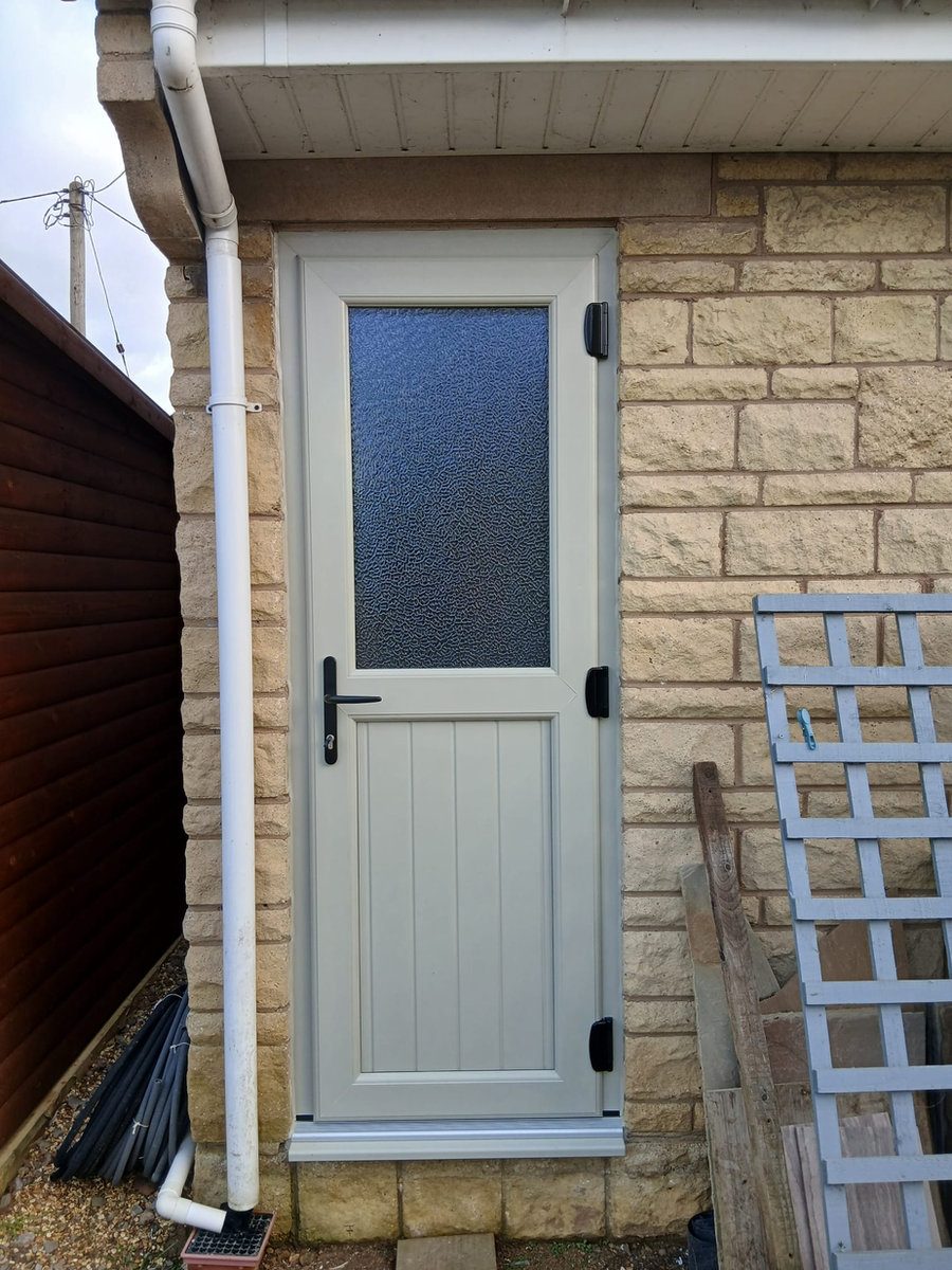 Cream half-glazed back door beside stone wall